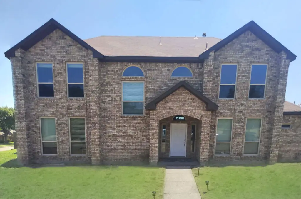 A two story brick house that has had window replacement